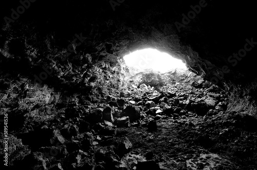The Light at the End of the Tunnel. A black and white image of a lava tube in Craters of the Moon National Monument in Idaho,approaching the opening to daylight.