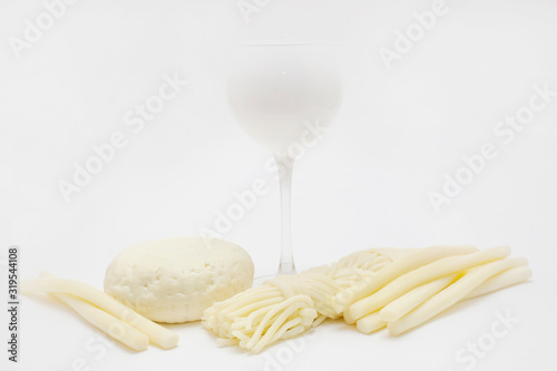 The cheeses are laid out around a white glass isolated on a white background. The concept of types of cheese.