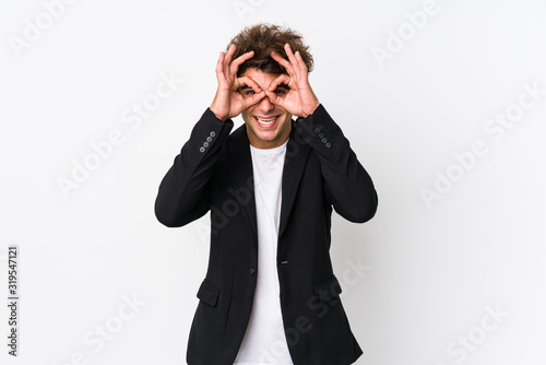 Young caucasian business man against a white background isolated showing okay sign over eyes