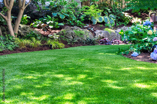 This beautiful backyard woodland garden features a maintenance free lawn made of natural looking artificial grass, a huge landscaping trend for small spaces. photo