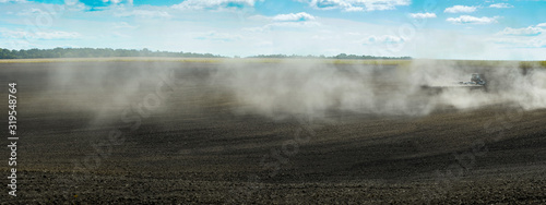 a cloud of dust on a plowed field farms are in preparation for sowing.