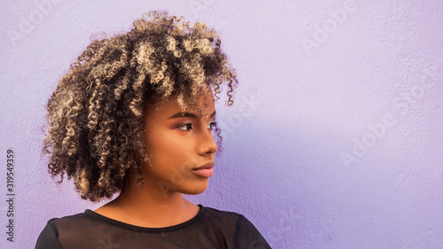 Foto Mujer joven afrodecendiente cabello risado suelto mirando hacia un lado sobre fo