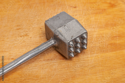 Hammer for beating meat on a wooden cutting board.