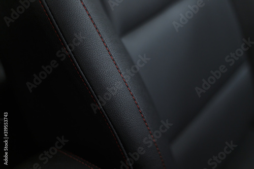 Naklejka Part of stitched leather black leather car interior. Modern luxury car black perforated leather interior. Car leather interior details. Decorative seam