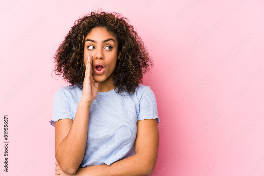 Young african american woman against a pink background is saying a secret hot braking news and looking aside Young african american woman against a pink background is saying a secret hot braking news and looking aside