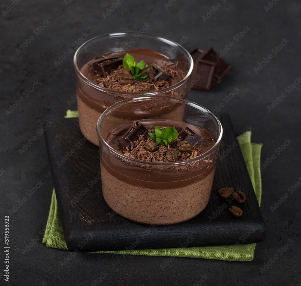 Italian dessert creamy chocolate and coffee jelly, Panna cotta with chocolate pieces in a glass Cup on a dark background