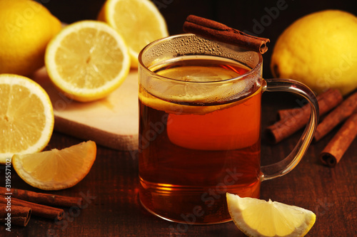 A mug with hot tea with lemons and cinnamon sticks 