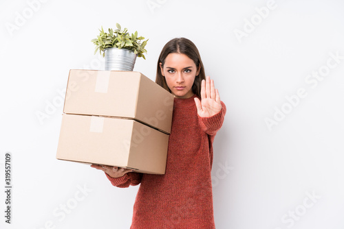 Young caucasic woman holding boxes isolated standing with outstretched hand showing stop sign, preventing you.