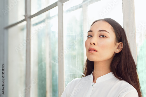 Freestyle. Young woman standing near window looking camera playful close-up