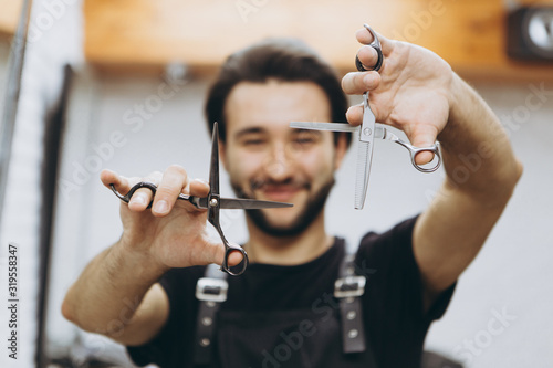 a stylish and attractive bearded barber holds professional hair clippers on his outstretched arms. Focus on the scissors. concept for barbershops, beauty salons and hairdressers