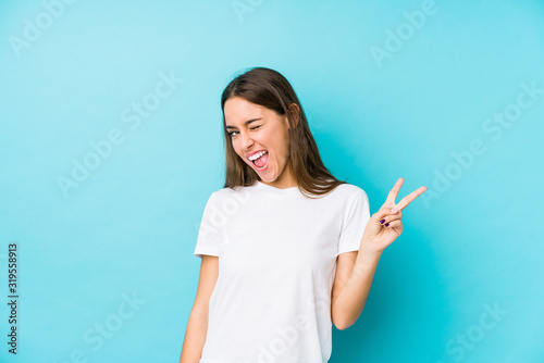 Young caucasian woman isolated joyful and carefree showing a peace symbol with fingers.