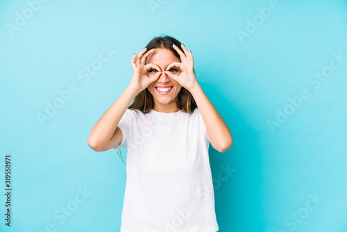 Young caucasian woman isolated showing okay sign over eyes