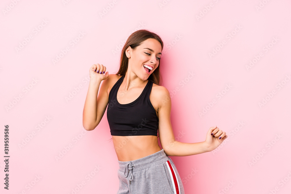 Young caucasian fitness woman posing in a pink background dancing and having fun. Young caucasian fitness woman posing in a pink background dancing and having fun.