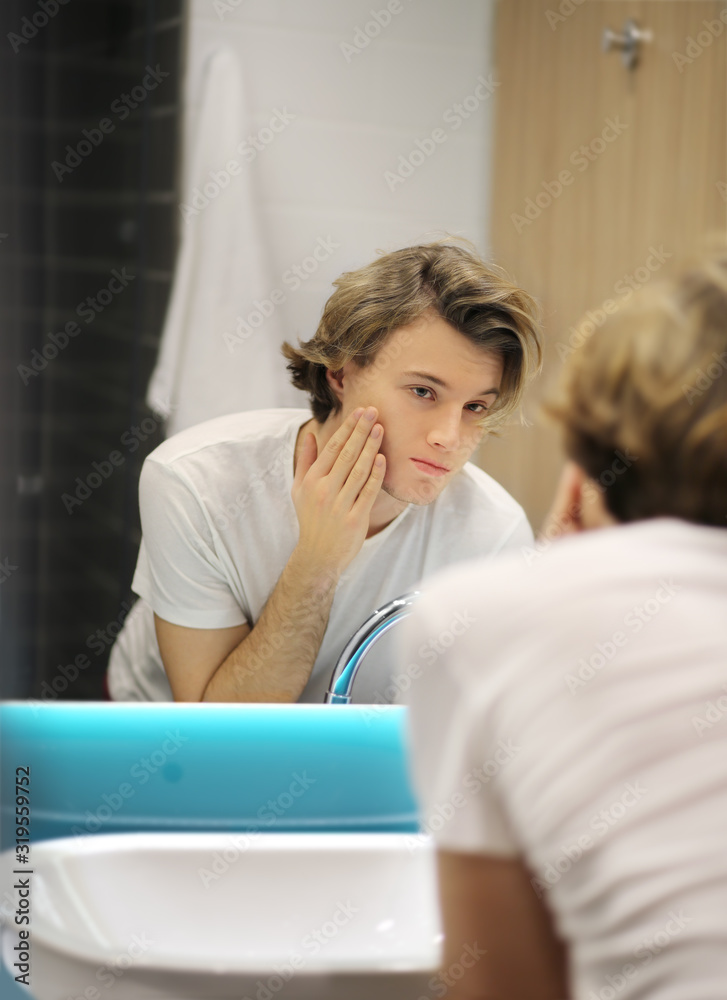 young man looking in the mirror,combing his hair,looking at problems on face