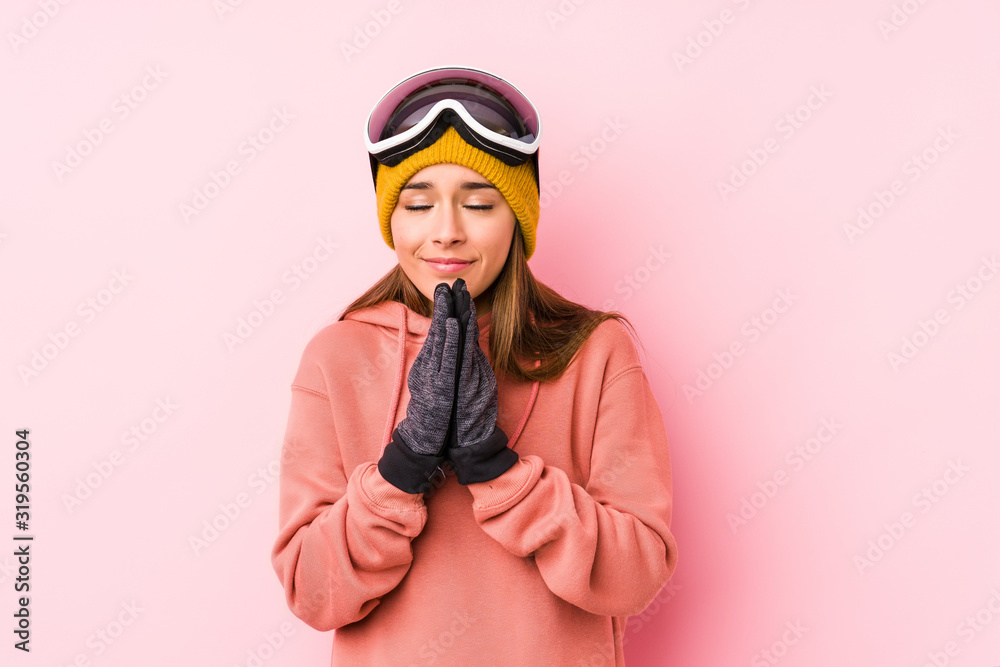 Young caucasian woman wearing a ski clothes isolated holding hands in pray near mouth, feels confident. Young caucasian woman wearing a ski clothes isolated holding hands in pray near mouth, feels confident.