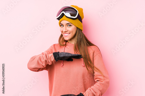Young caucasian woman wearing a ski clothes isolated holding something with both hands, product presentation.