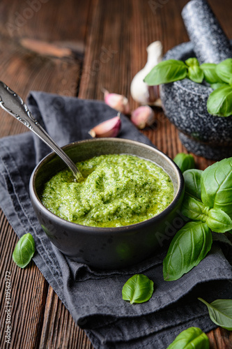 Photography Homemade fresh basil pesto sauce in a bowl, decorated with leaves, garlic and mo