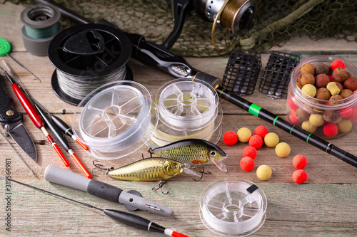 Fishing rods and spinnings in the composition with accessories for fishing on the old background on the table