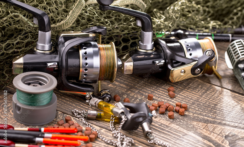 Fishing rods and spinnings in the composition with accessories for fishing on the old background on the table