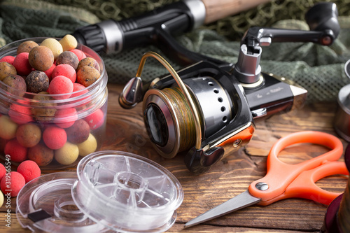 Fishing rods and spinnings in the composition with accessories for fishing on the old background on the table