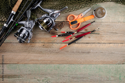 Fishing rods and spinnings in the composition with accessories for fishing on the old background on the table