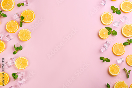 Frame made of lemon slices, mint and ice on pink background, top view with space for text. Lemonade layout