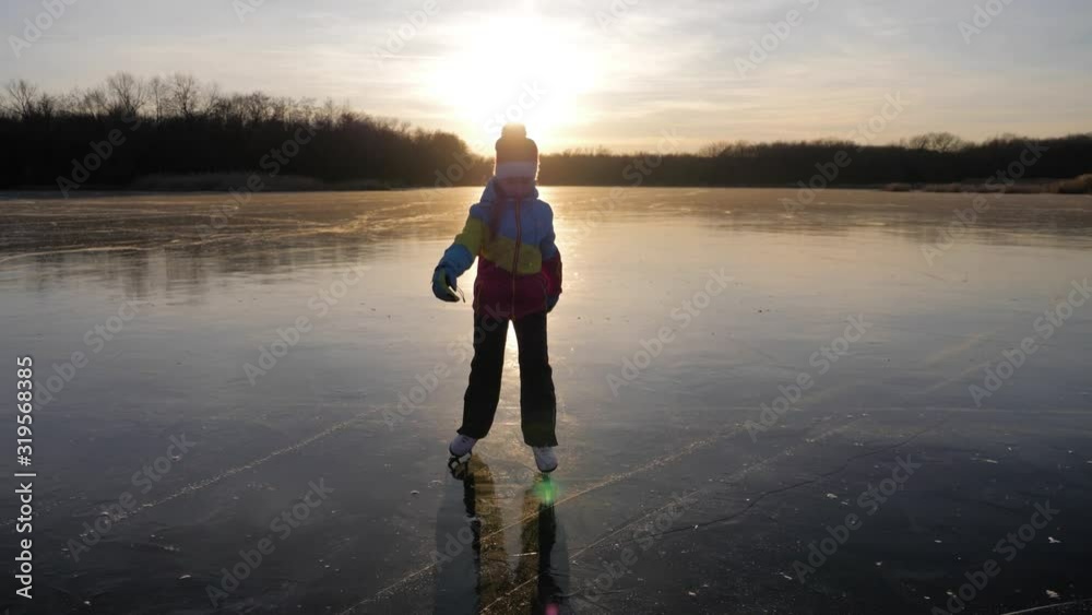 Cute little girl is going skate outdoors at sunset. A schoolgirl enjoying ice skating at frozen lake in winter season. Winter sports. Cute little girl is going skate outdoors at sunset. A schoolgirl enjoying ice skating at frozen lake in winter season. Winter sports.
