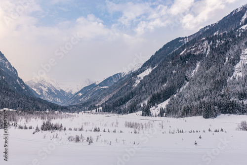 Winter mountain landscape in the Alps. The valley, meadow, trees and mountains covered with snow.