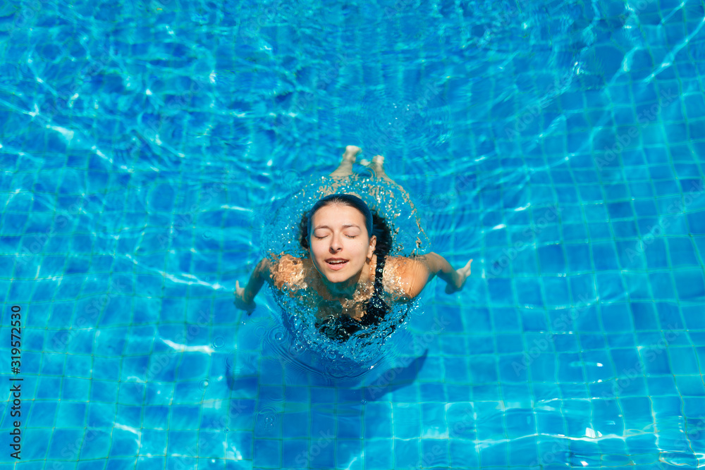 Young sexy slim woman relaxing in swimming pool with crystal blue water