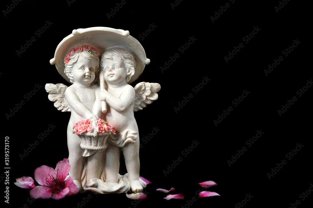 Fototapeta premium Two angels figurine isolated on black background with copy space. Love concept.