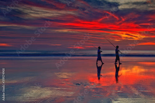 Fishermen silhouette under the colorful sunset in Seminyak 