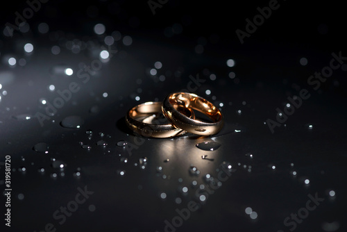 Wedding rings black background white rose drops
