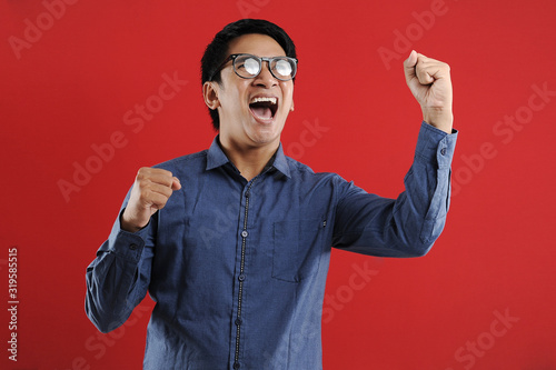 Young asian man happy and excited expressing winning gesture. Successful and celebrating