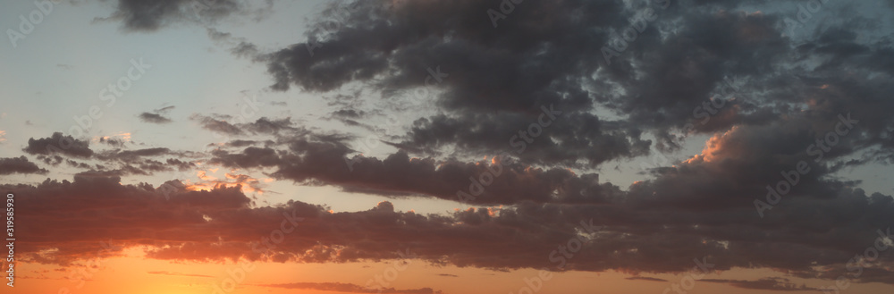 panoramic landscape showing the fiery burning colors of the sun setting in the clouds after a hot summers day in Australia