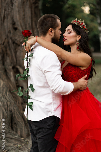 Beautiful romantic couple kiss closeup. Attractive young woman in red dress and crown with handsome man in white shirt are in love. Happy Saint Valentine s Day. Pregnant and wedding concept.