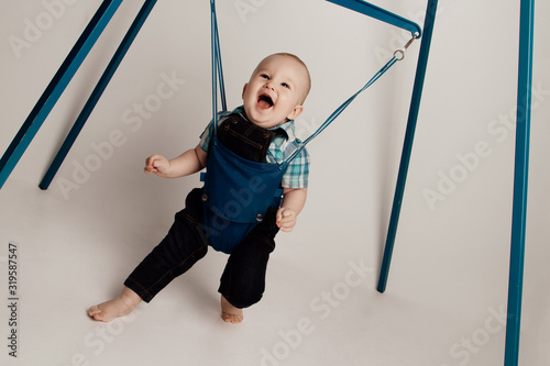 Jolly Baby boy bouncing in jumper  / jumping stand. photo