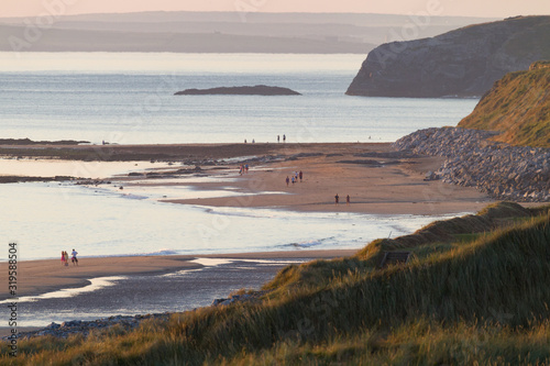 People waking on the beach in the distance at sunset on the west coast of Ireland near the coastal town of Ballybunion in county Kerry