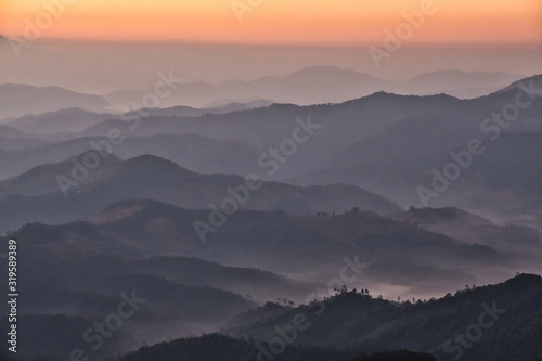 Mountain view misty morning of the hill around with the mist in valley with yellow sun light and cloudy sky background  sunrise at Phu chi phur viewpoint  Mae Hong Son Northern  Thailand.