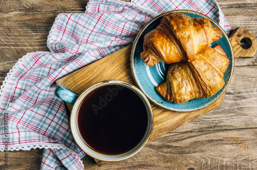 Coffee and croissant on rustic wooden table. French breakfast. Top view. Flat lay. Copy space.