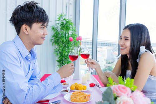 Valentine s day concept Happy Asian Young sweet couple having romantic the Lunch with clinking toasting wine glasses at the restaurant background.