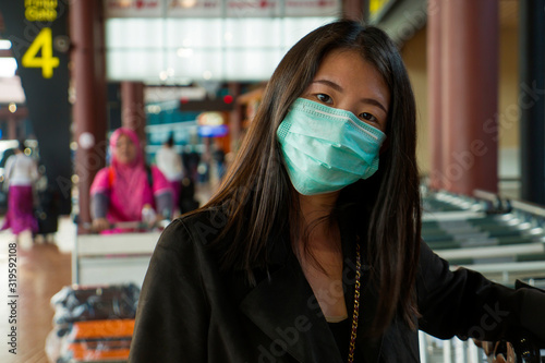 young beautiful and attractive Asian Chinese student at airport wearing protective facial mask against China Coronavirus epidemic outbreak spreading breathing syndrome