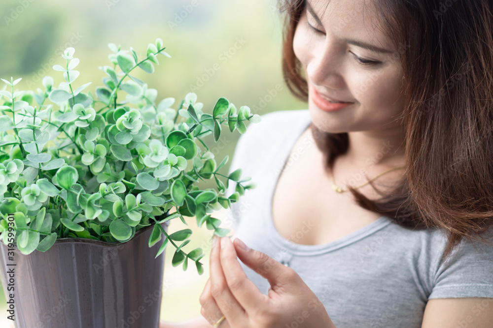 Closeup woman touching tree in pot with happy face in the morning Closeup woman touching tree in pot with happy face in the morning
