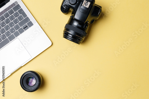 Photographer's workplace on a yellow background. Modern laptop, digital camera, lens, battery, smartphone. Minimalism. Top view. Copy space. Equipment for the photographer. The concept of freelancing