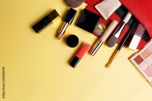 Set of professional elite decorative cosmetics for makeup on a yellow background. The concept of beauty and fashion. A red makeup bag with cosmetic beauty products: lipstick, eye shadow, foundation