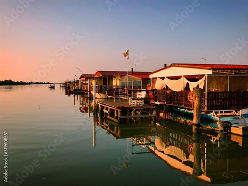Foto Boat House Moored At Harbor Against Sky During Sunset