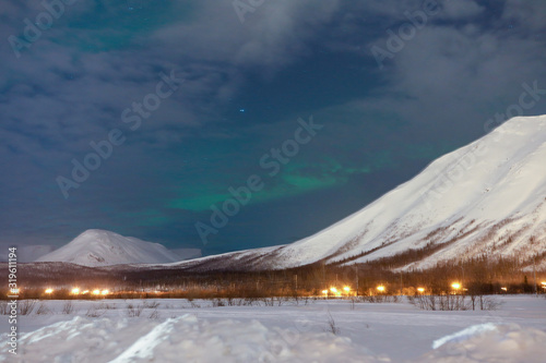 Northern lights behind the cloon the background-night mountains with snow photo