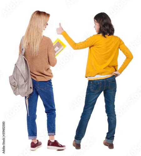 Back view of two young girl in sweater showing thumb up.