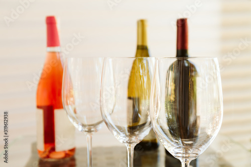 Wine tasting set in the light airy environment. Custom wine tasting concept. Glasses of wine and bottles on the glass table and light background.