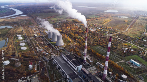 Power plant generating heat and electricity. High pipes and cooling towers are visible. Aerial view.