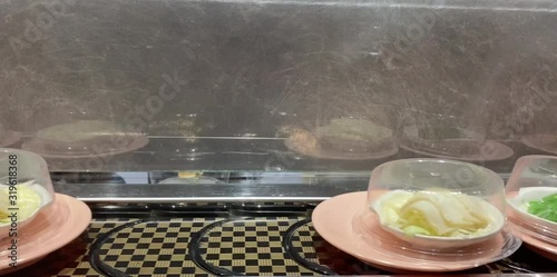 Many kinds of Japanese food such as sushi, sashimi, onigiri or side dishes, arrange to pieces fit in a bite with a cover on the conveyor belt to pass slowly. Customers can choose to eat as satisfied photo